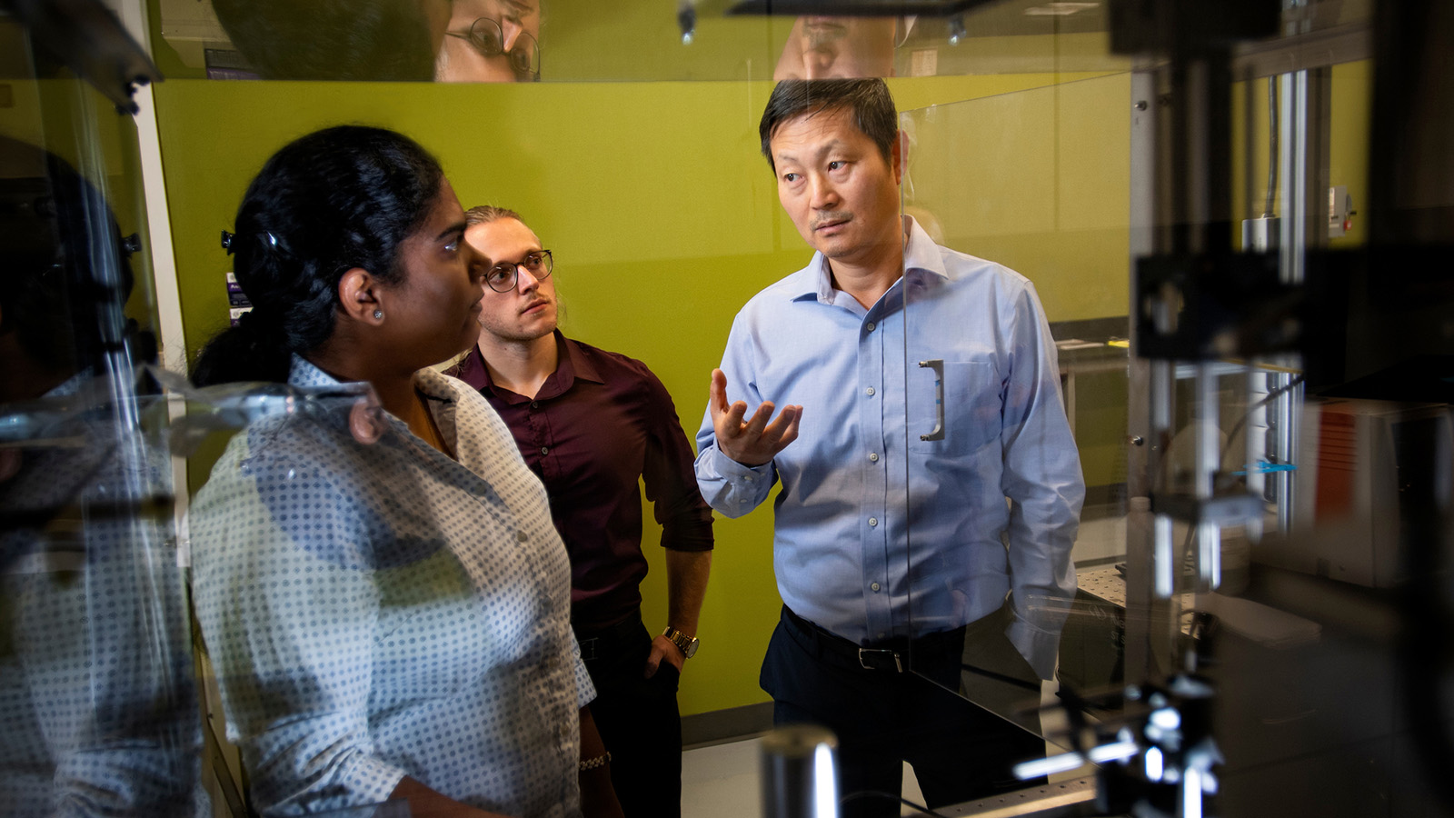 Faculty member Tae-Youl Choi works with two students in the lab.