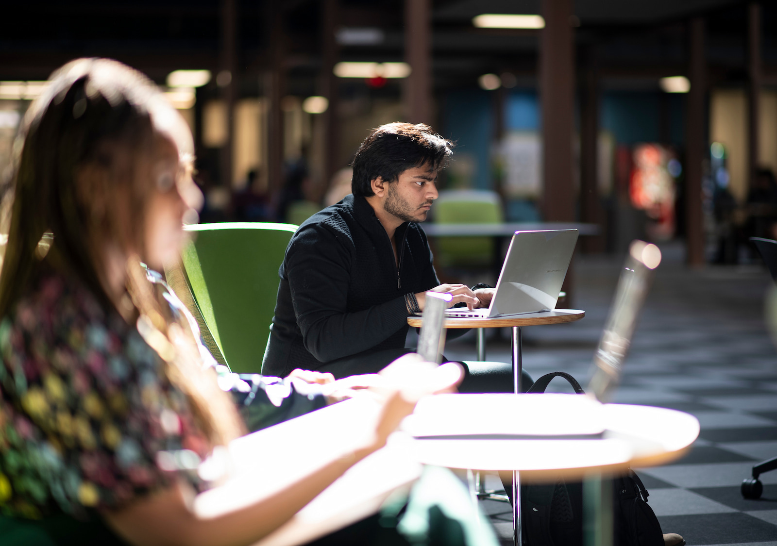 Two students work on their laptops