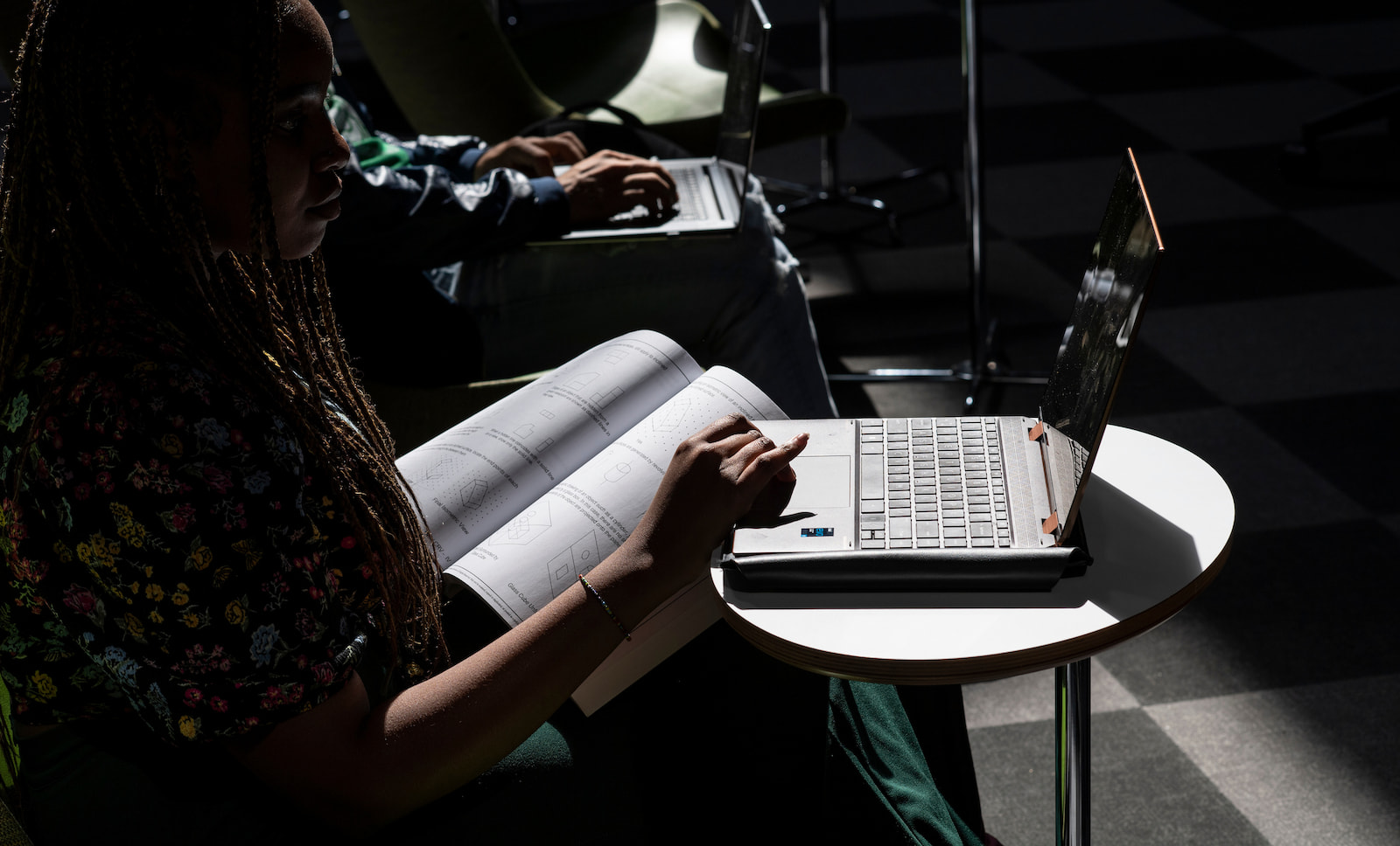 A student works with a book and laptop