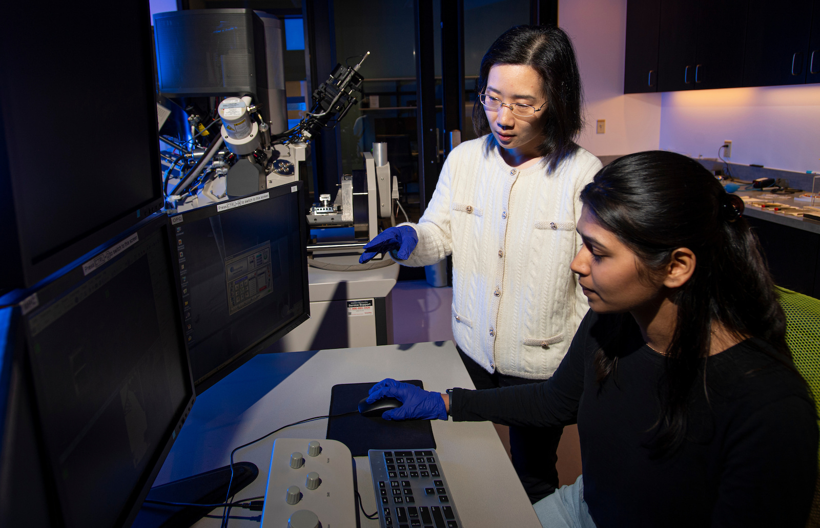 A scientist and student work on a computer in a lab