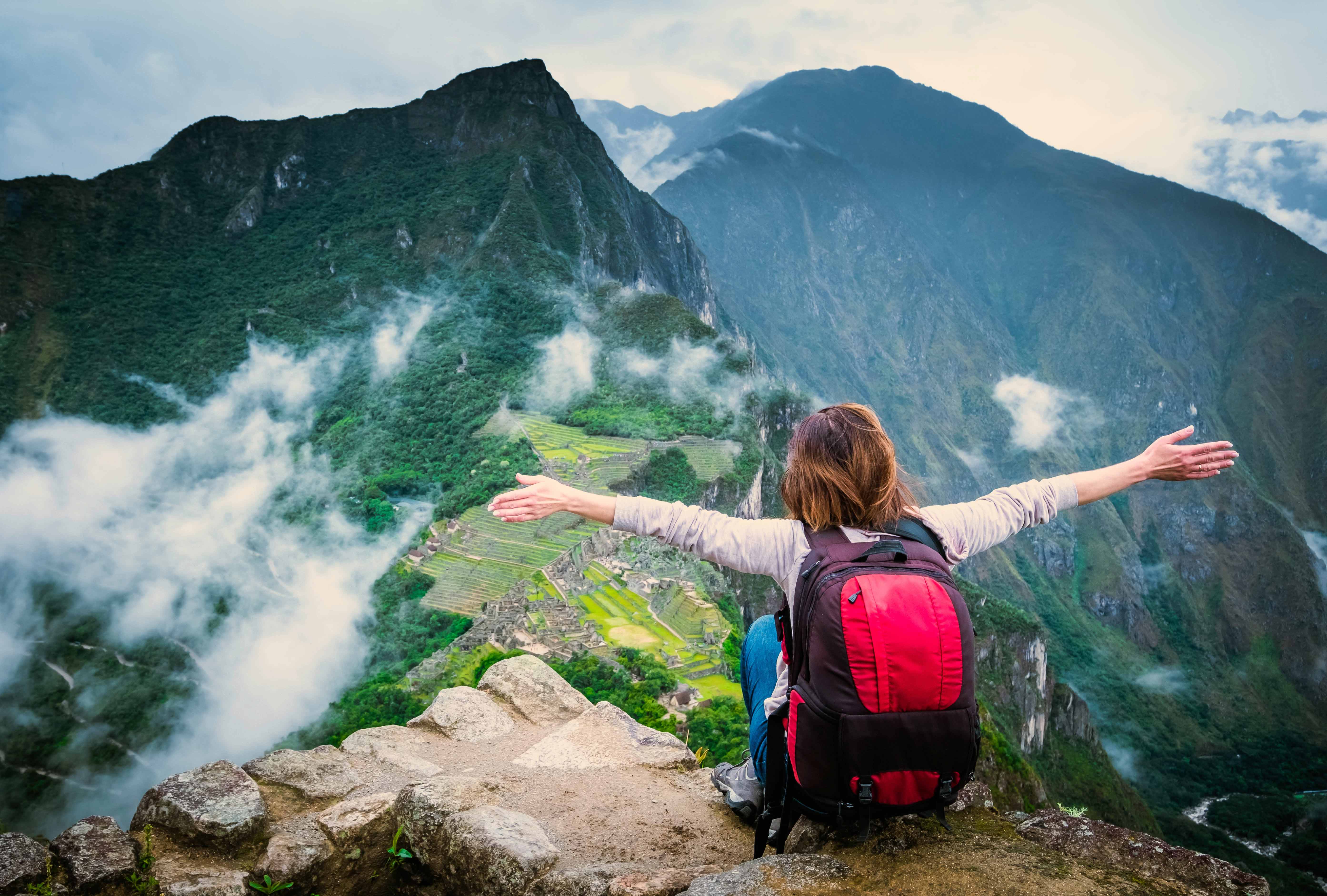 Woman with arms wide on a mountain overlooking a city