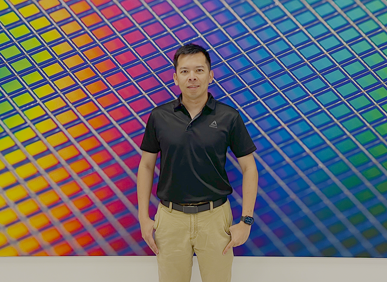 Huy Nguyen poses in front of colorful background