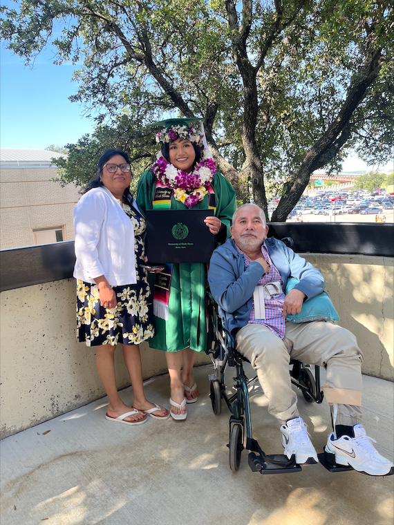 Lupita poses in commencement regalia with her parents