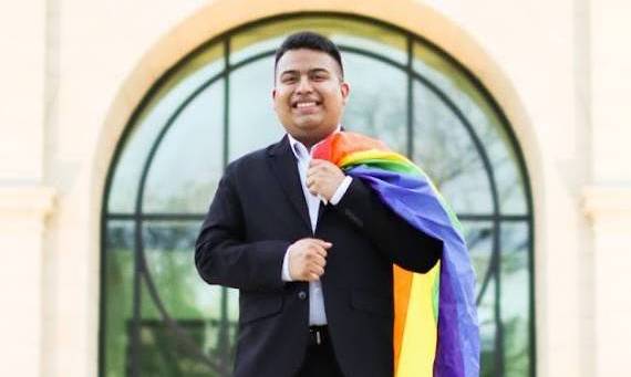 David Munoz-Sarabia with a Pride flag draped over their shoulder